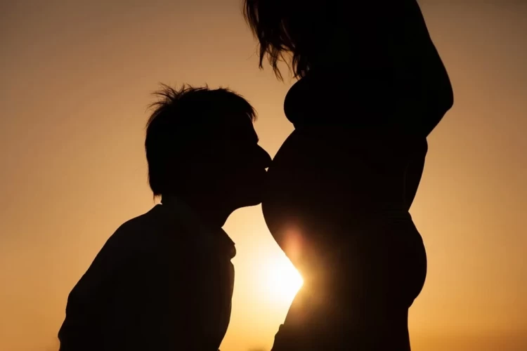 чоловік цілує вагітну жінку у живіт 