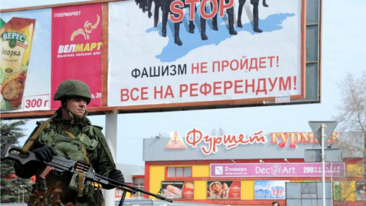 зелений чоловічок і плакат із закликом іти на кримський референдум
