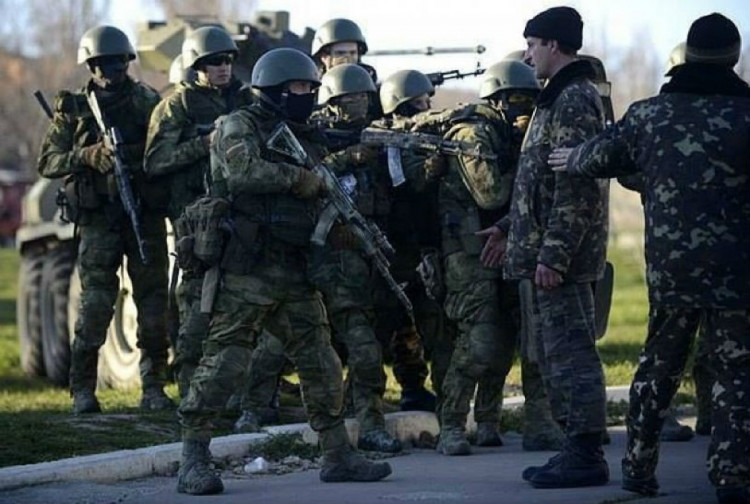 беззбройний український військовий в якого ціляться зелені чоловічки