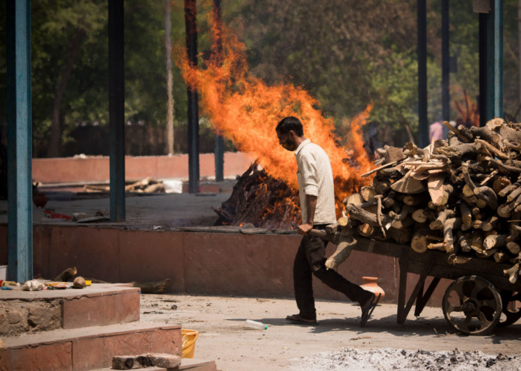 человек в Индии тянет дрова в крематорий