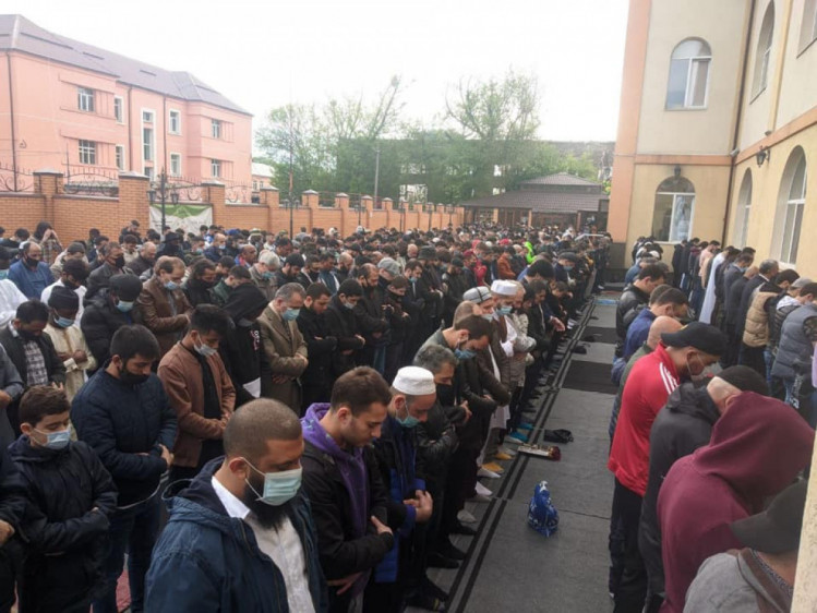 мужчины молятся во дворе мечети