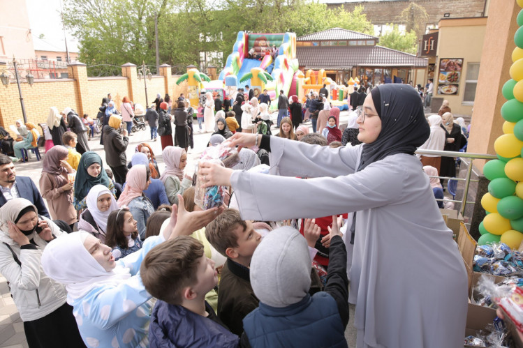 мусульманка раздает конфеты детям в честь ураза байрам