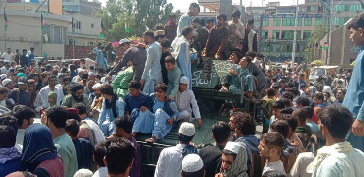 Бойцы талибов и местные жители сидят на автомобиле афганской национальной армии в Джалалабаде.