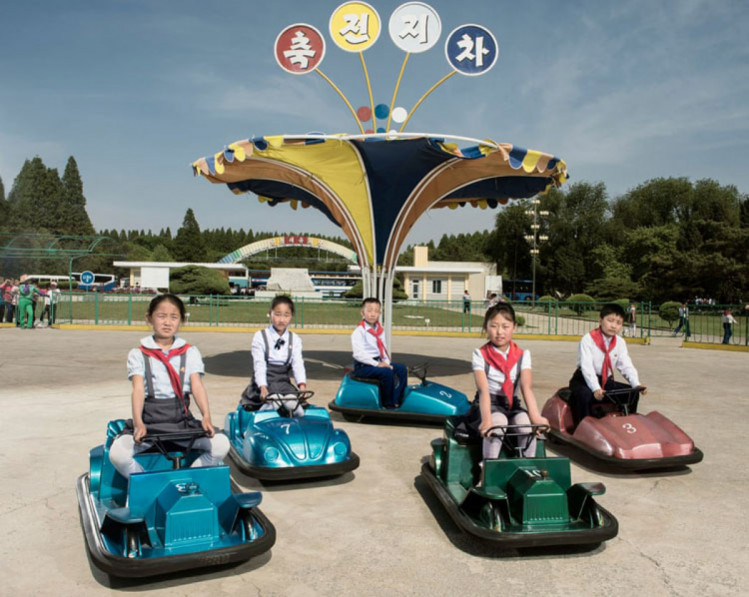північнокорейські діти катаються на машинках