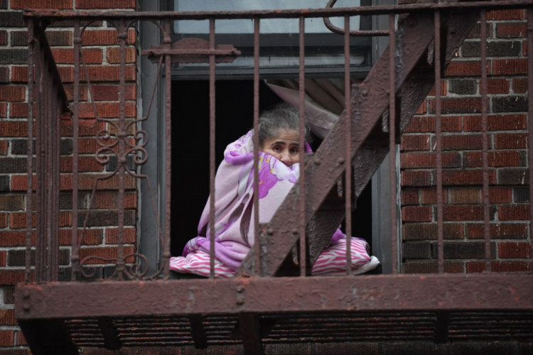 женщина завернувшись в одеяло ждет, пока ее спасут во время пожара дома