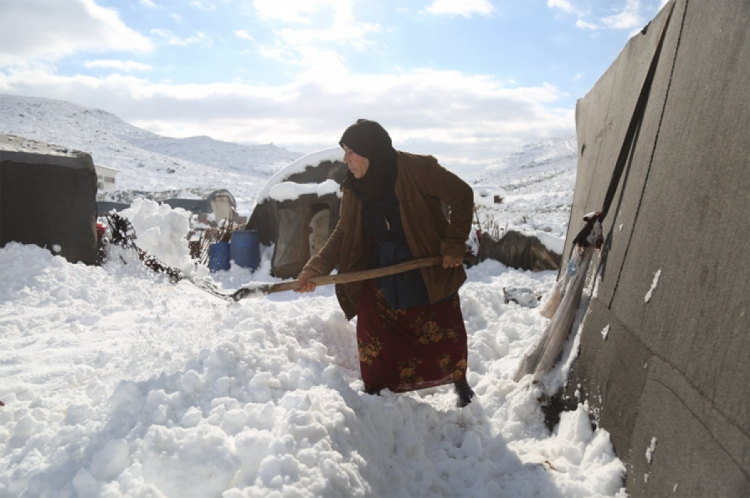 сирийская беженка откапывает свою палатку от снега